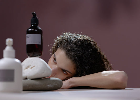 A woman looking at a bottle of shampoo and a bottle of conditioner